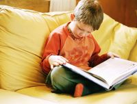 Boy reading on yellow couch.